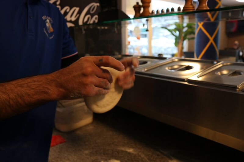 Pizza wird mit Tomatensauce bestrichen