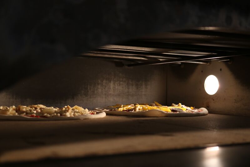 Pizza wird mit Tomatensauce bestrichen